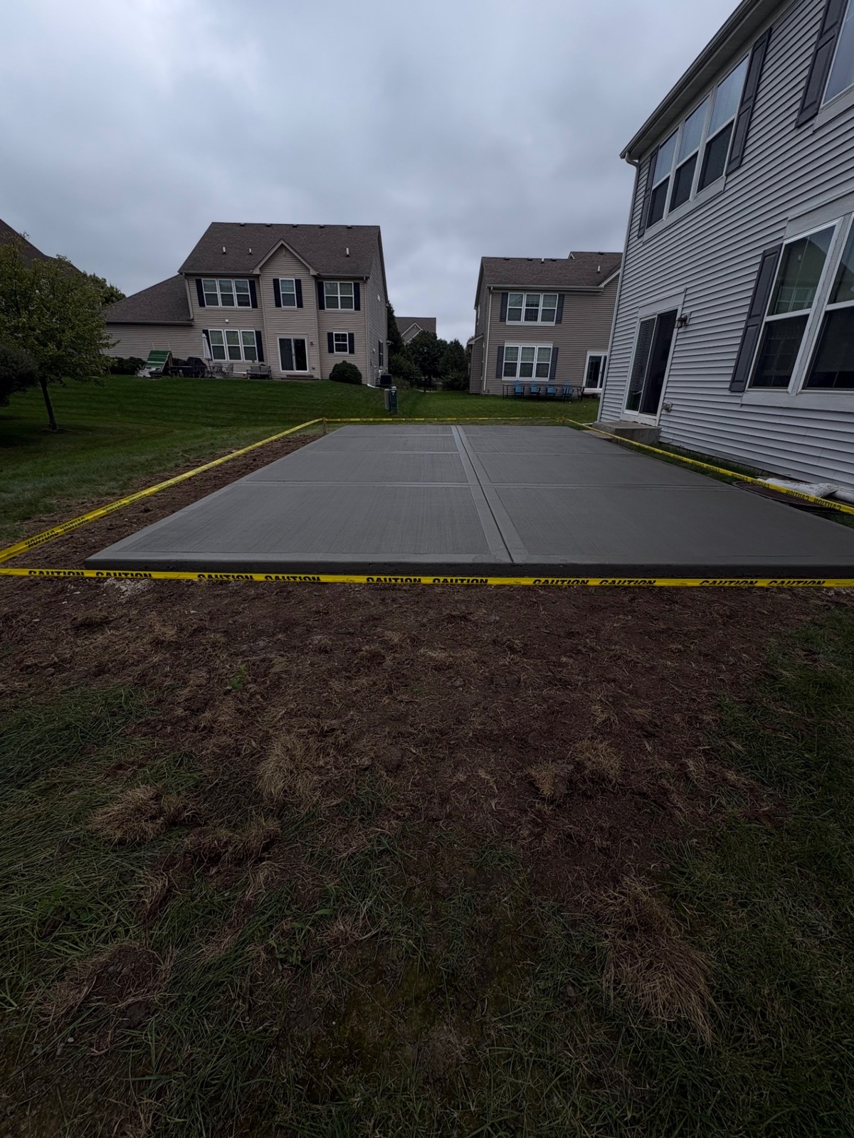 Wide view of new concrete patio with caution tape