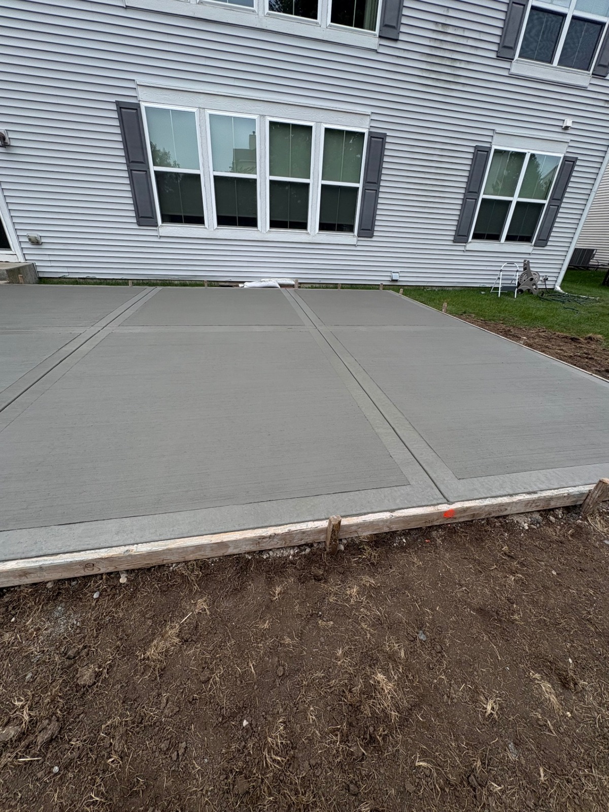 Freshly poured backyard concrete patio with wooden forms